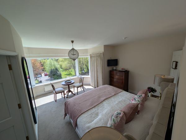 Spacious double bedroom with bay window and garden view