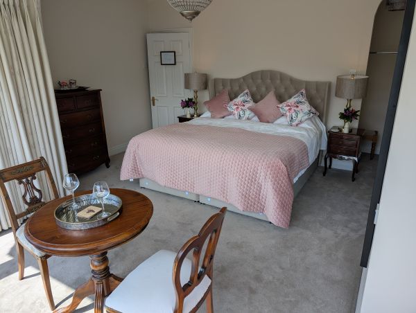Elegant double bedroom with pink throw and seating area